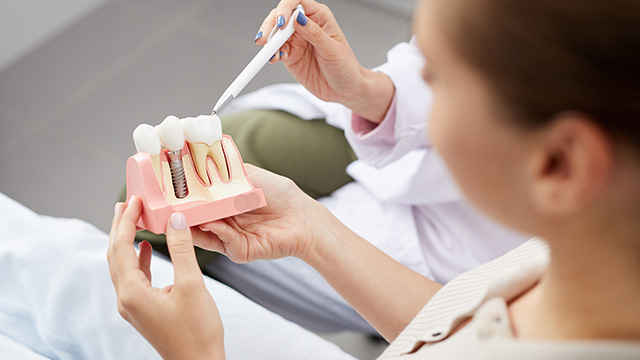 A dental professional examining a patient s teeth with a magnifying glass.